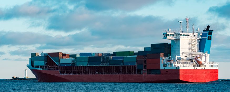 Full red container ship moving in still water
