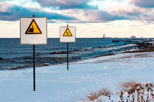 Two yellow warning signs on the winter beach