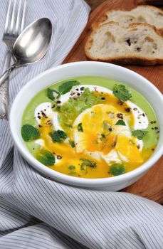 Pea puree soup with poached egg, sour cream, mint leaves seasoned with spices.