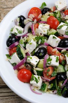 Greek salad orzo pasta with black olive, red onion and cucumber, cherry tomatoes, feta and herbs. Vertically shot. View from above