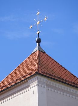Golden cross of a church on red tile roof