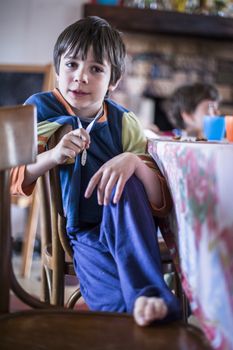 portrait of child dressed in pajamas sitting on chair at home with a medal at the neck