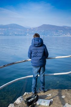 teenager on the shore of Lake Maggiore are fishing in the winter on a sunny day