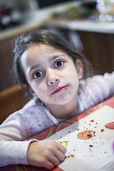 portrait of serious little girl with cake crumbs dirty mouth looking towards camera lens