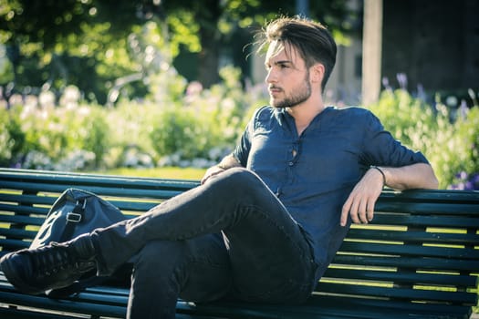 One handsome young man in urban setting in European city, a city park