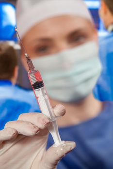 A close-up of a female doctor out of focus in hospital, holding a syringe in hospital. Vaccine