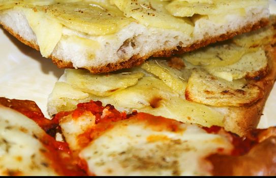 close up of two slices of pizza with tomato, mozzarella and potatoes