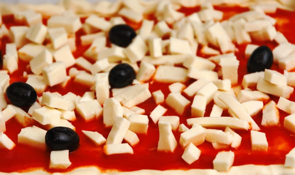 Raw pizza decorated mozzarella, black olives and tomato sauce ready to be baked