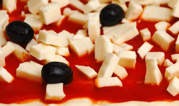 Raw pizza decorated mozzarella, black olives and tomato sauce ready to be baked