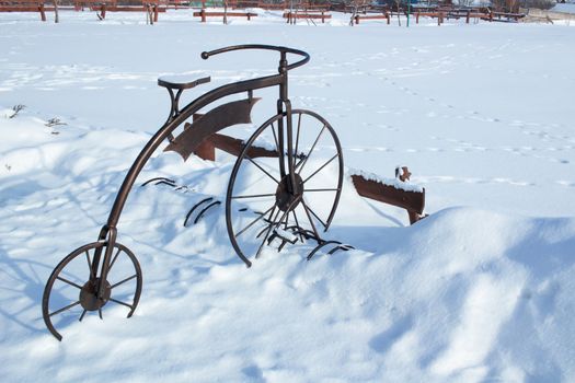 Iron sculpture of bicycle in white snow on wintertime