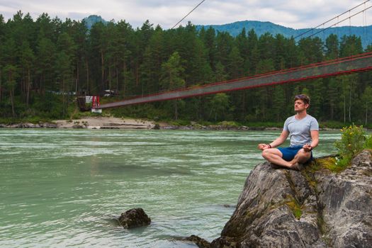 Young man spending time at riverbank of mountain river