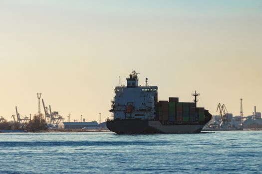Modern grey container ship moving in still water