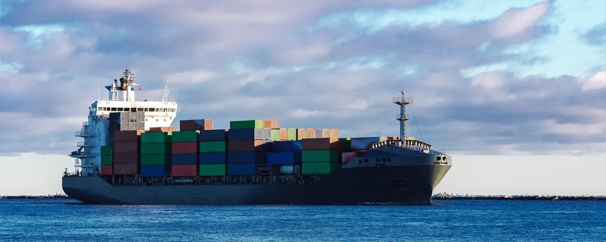 Modern grey container ship moving in still water