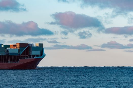 Full red container ship moving in still water