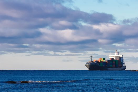 Modern grey container ship moving in still water