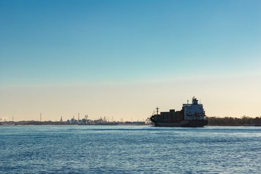 Modern grey container ship moving in still water