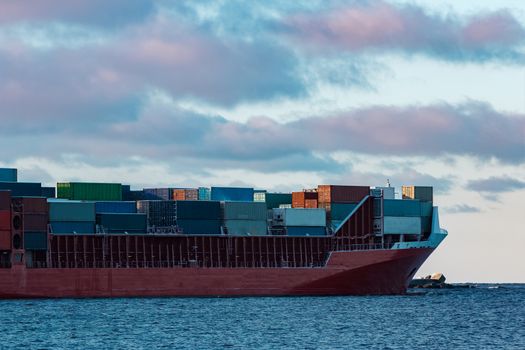 Full red container ship moving in still water
