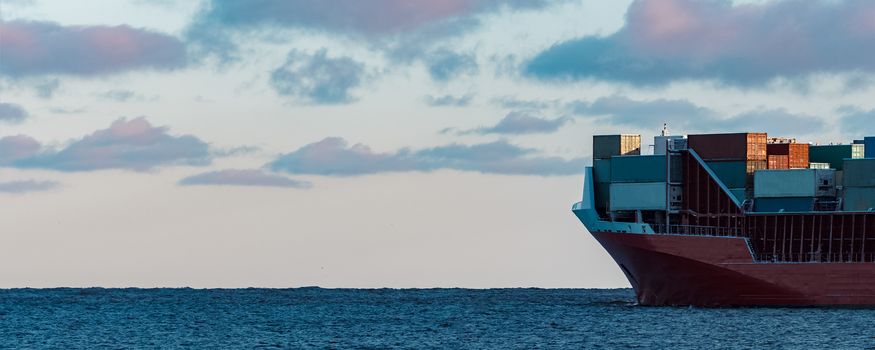 Full red container ship moving in still water
