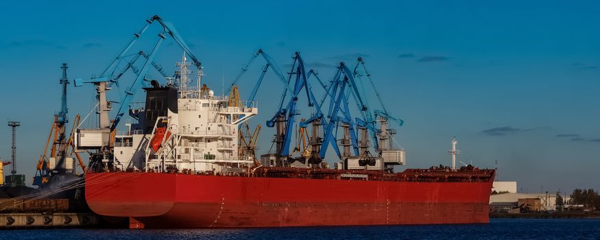 Red cargo ship loading in the port of Riga, Europe