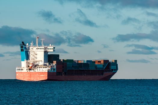 Full red container ship moving in still water