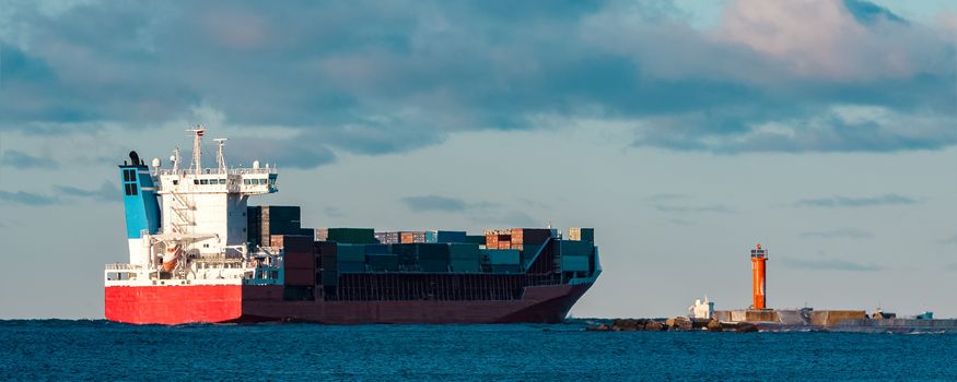 Full red container ship moving in still water