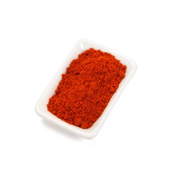 Red pepper pod on pile of chili powder isolated on white.