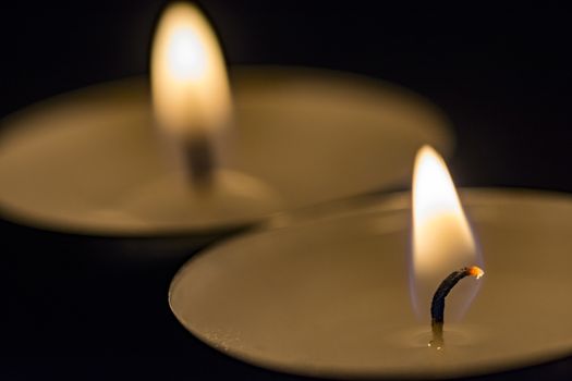 two burning candles in black background