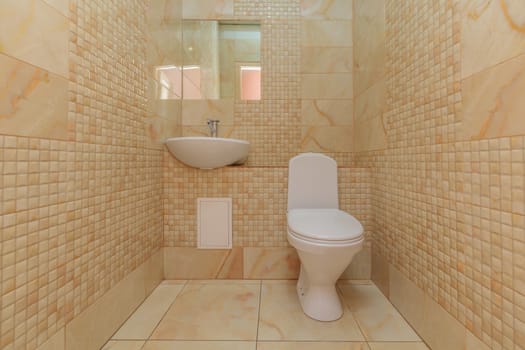 Toilet bowl in the toilet room. Restroom with brown tile decoration