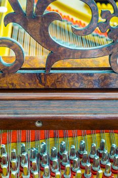 Close up of an antique grand piano showing the pins and strings.