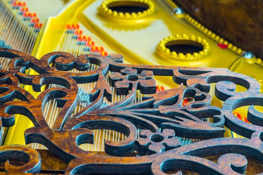 Close up of an antique grand piano showing the sounding board, strings and music rack