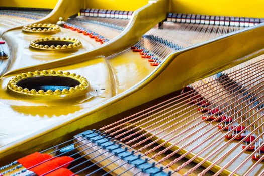 Close up of an antique grand piano showing the sounding board and strings.