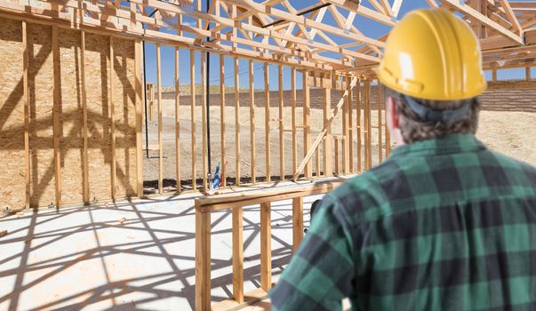 Contractor Standing Inside Construction Framing of New House.