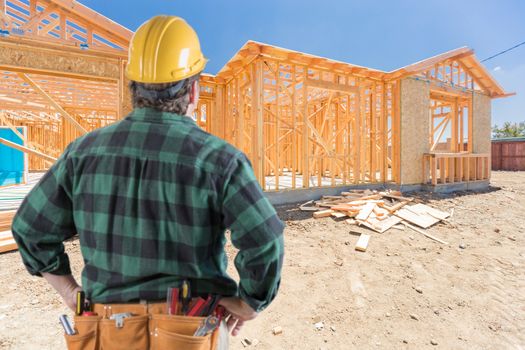 Contractor Standing Outside Construction Framing of New House.