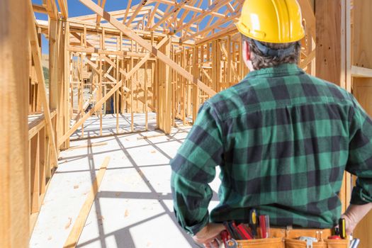 Contractor Standing Inside Construction Framing of New House.