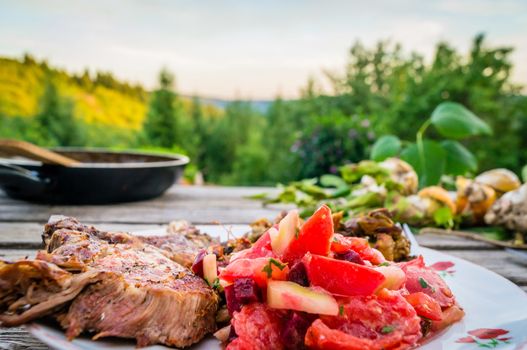 Nice meal of pork ribs and fresh tomatoes eaten outside in summer