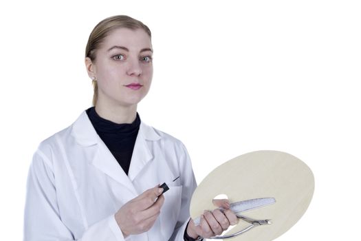 Young woman in a white coat with a manicure tool and a palette