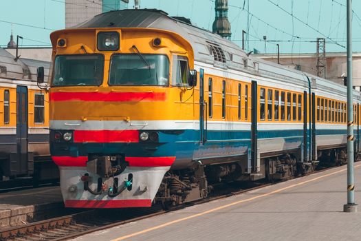 Old yellow passenger diesel train moving at the terminal