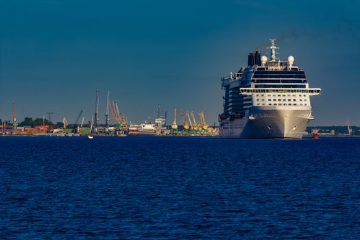 Giant white passenger ship moving past the port on a clear day
