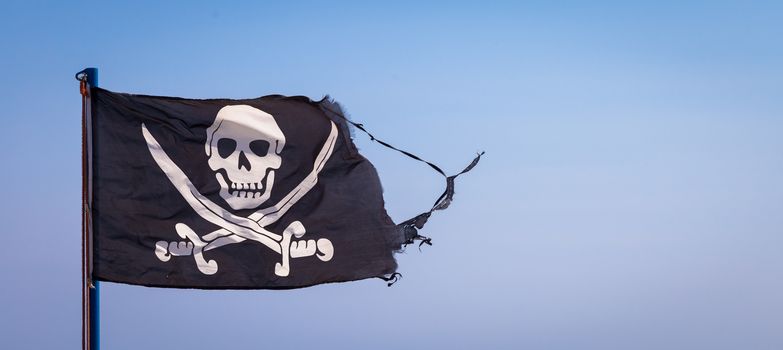 A damaged pirate flag during a strong windy day, with copyspace