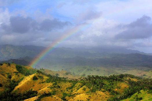 Rainbow in the sky against the background of Cordilleras in the Dominican Republic. Aerial view 