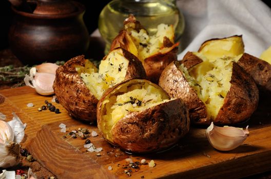 broken baked potato with spices and herbs on a wooden board