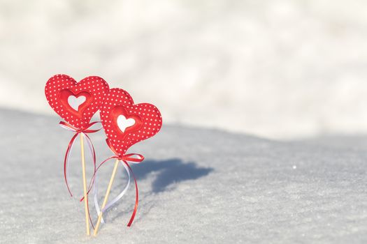 Beautiful valentine holiday background with two checkered hearts on cane, white snow surface.