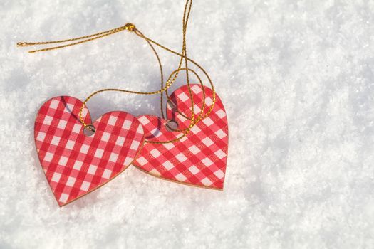 Beautiful valentine holiday background with two checkered motley hearts on white snow surface.