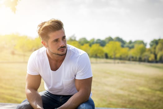 Attractive muscular man in city park in a nice summer day
