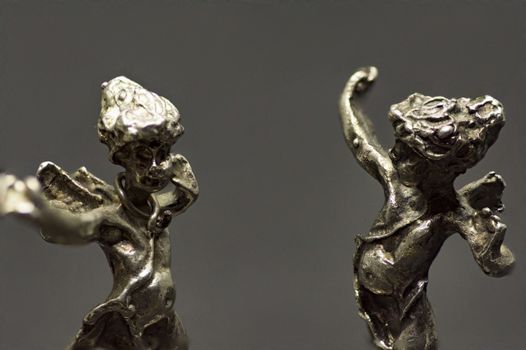 two metallic figurine angels are dancing