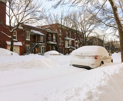 Urban winter street with cars stuck in snow. Montreal, Quebec, Canada.