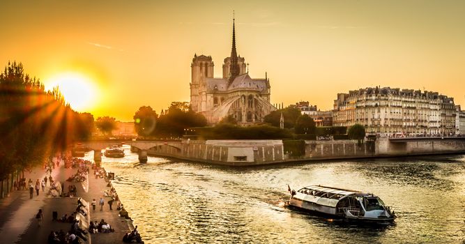Sunset over Paris wharf and Notre-dame in summer with a peniche boat passing by