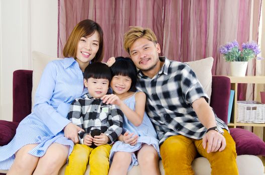 Portrait of asian family siting on the sofa at home.