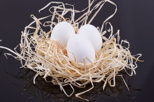 Three chicken eggs in the nest like On a black background
