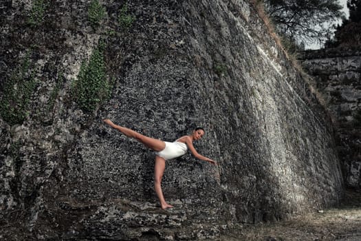 portrait of a beautiful young ballerina posing in front of a big wall of an old castle